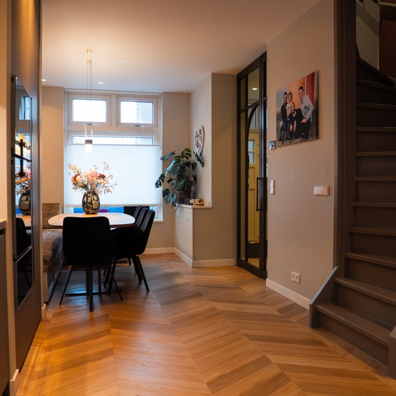View from the hallway into the dining area with herringbone floor, custom steel-framed door by Wood Creations and extended living space in the renovated Geuzenkwartier home