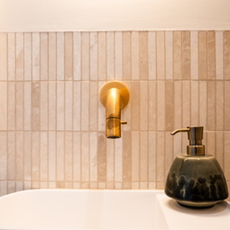 Detail of the bath with a gold wall light and green soap dispenser