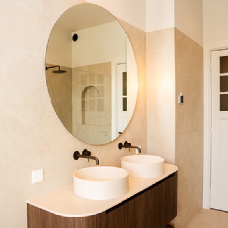 Main bathroom with a double washbasin, round mirror and panel door