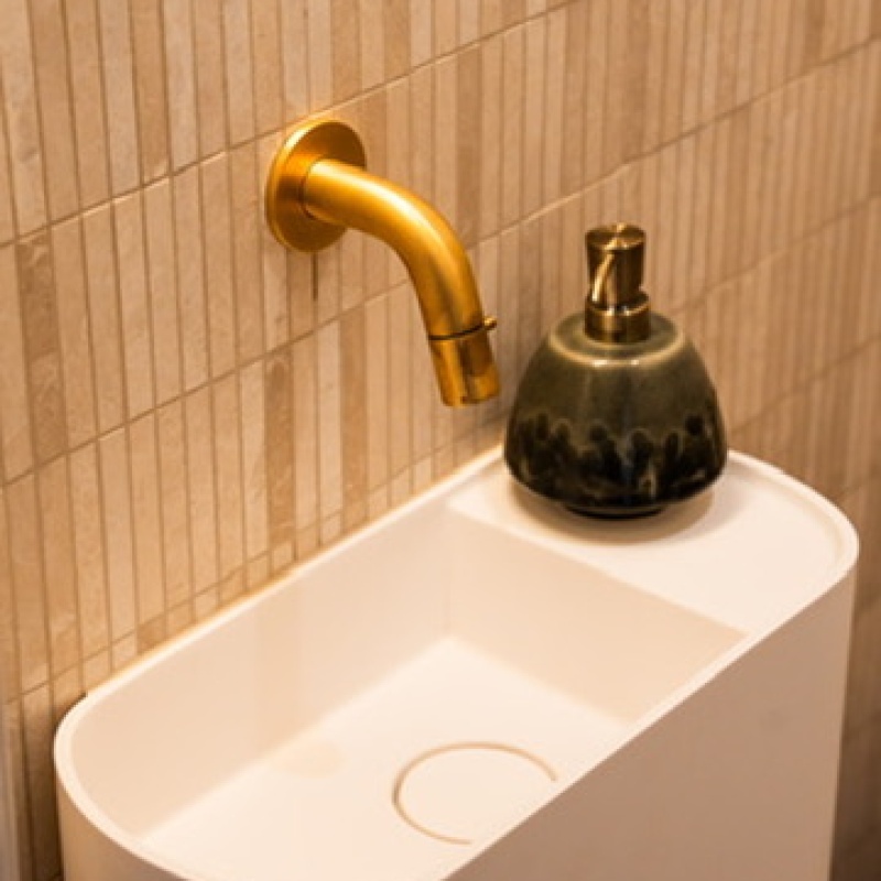 Detail of the small basin with a gold tap in the toilet