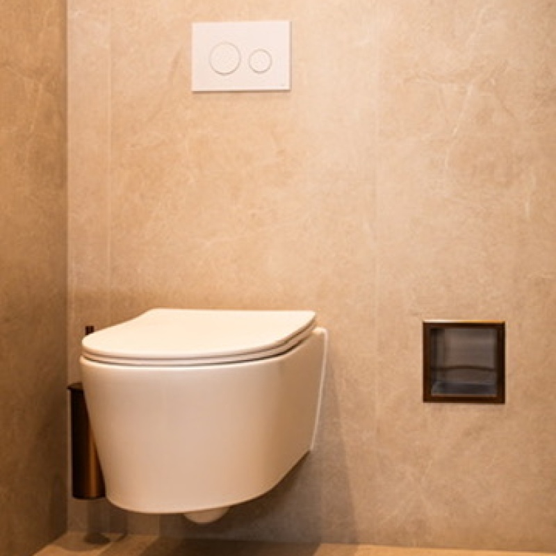 Wall-hung toilet with beige marble-look tiles and a recessed niche