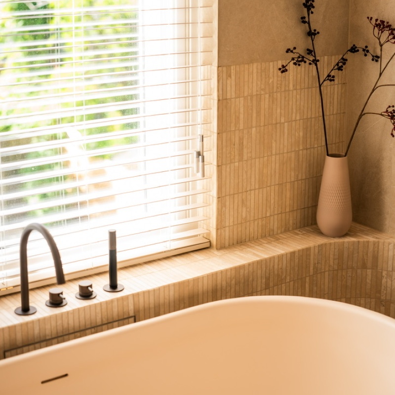 Detail of the freestanding bath with a black tap by the window