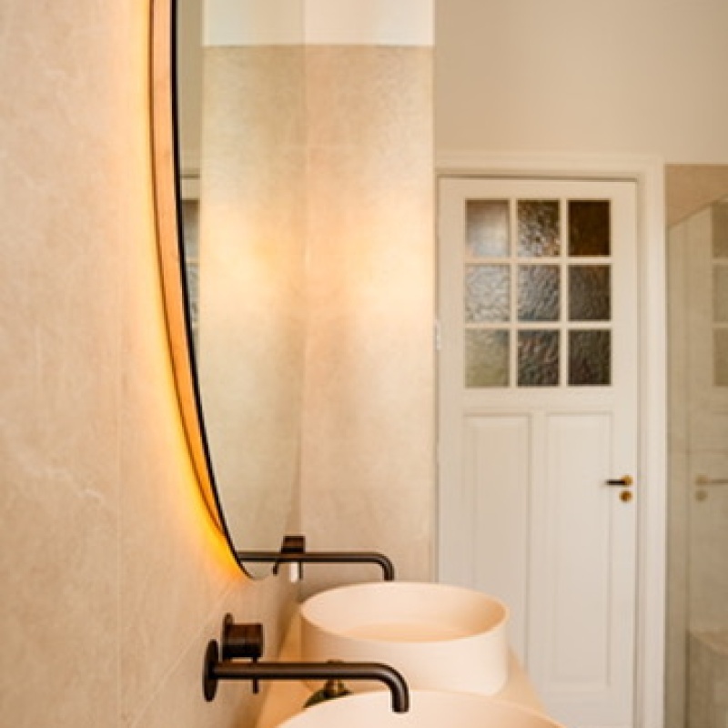 White round basin with a black wall-mounted tap beneath a mirror