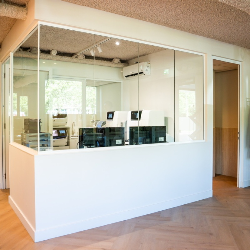 Technische ruimte achter glas met apparatuur en een garderoberek